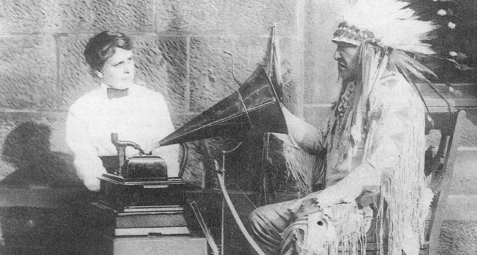 Amerikanska musiketnologen Frances Densmore tolkar sångtexter från en fonografinspelning tillsammans med Mountain Chief, svartfotsindianernas hövding, på Smithsonian Institution 1916.